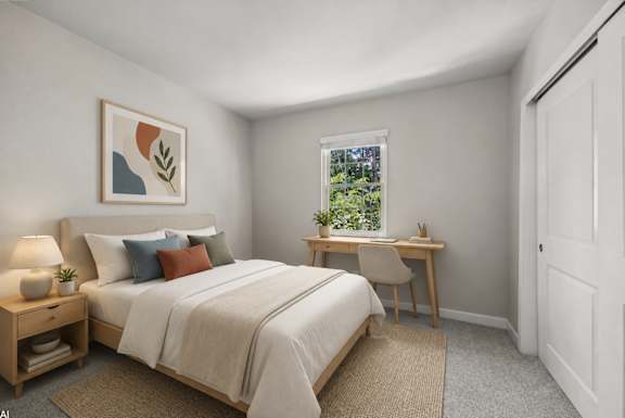A bedroom with a bed, desk, chair, and lamp.
