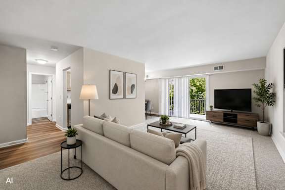 A living room with a white couch, a coffee table, and a television.