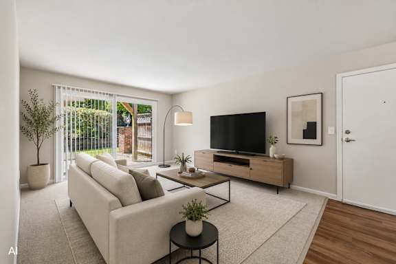 A living room with a white couch, a black TV, and a plant on a table.