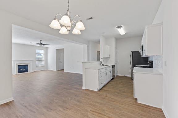 an empty kitchen and living room with white cabinets and a fireplace at Four Bridges, Liberty Township, OH, 45044-8380