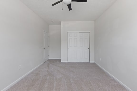an empty living room with a ceiling fan and a white door at Four Bridges, Liberty Township, OH