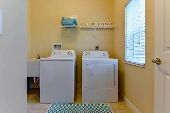A laundry room with two washing machines and a shelf above them.