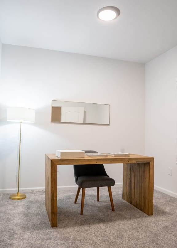 a desk with a chair and a lamp in a room with white walls and carpet