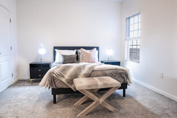 a bedroom with a bed and a stool in front of a window at Waterstone Landing, Ohio