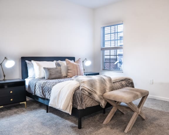 a bedroom with a bed and a stool in front of a window at Waterstone Landing, Perrysburg