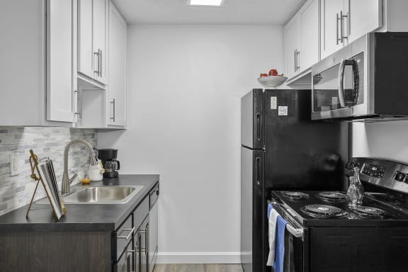 Kitchen with white cabinets and a black stove and refrigerator