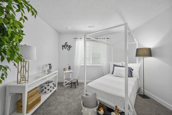 White bedroom with a white canopy bed and a white desk