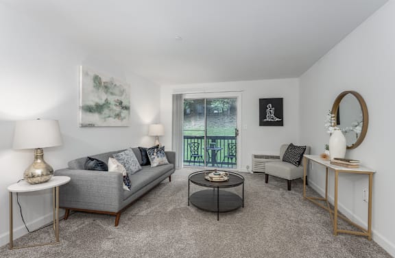 A living room with a grey couch, a coffee table, and a mirror.