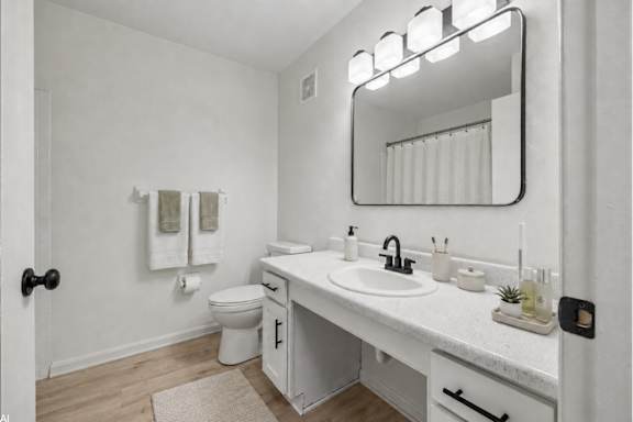 A white bathroom with a toilet, sink, mirror, and towel.
