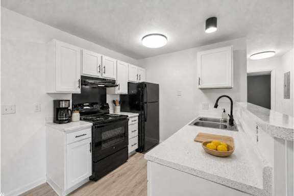 A kitchen with black appliances and white cabinets.