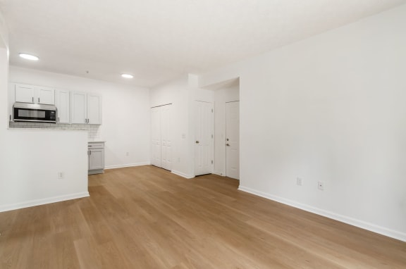 an empty living room and kitchen with white walls and wood floors