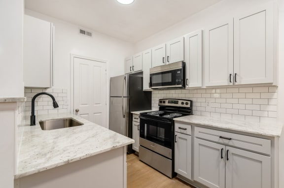 a kitchen with white cabinets and stainless steel appliances