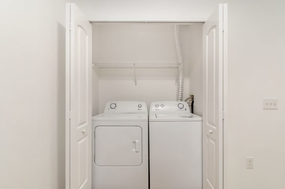 a white washer and dryer in a room with white walls and a door