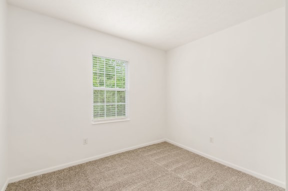 a bedroom with white walls and a window