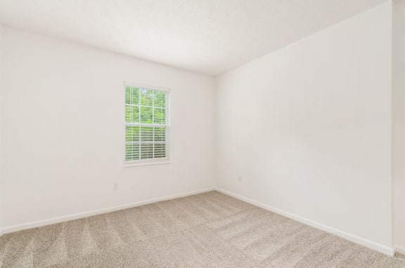 a bedroom with white walls and a window