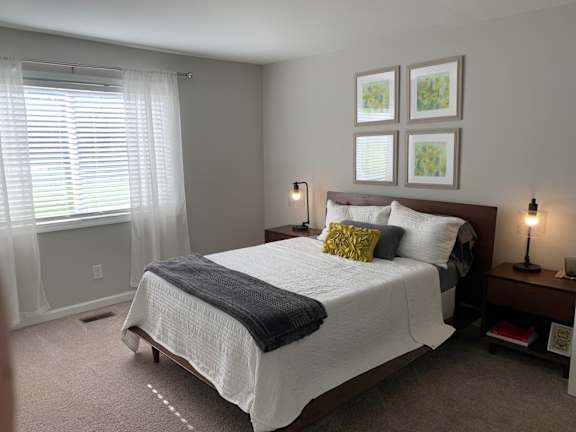 A bedroom with a large bed and a window with blinds. at 7 Pointe Apartments, Indianapolis, Indiana