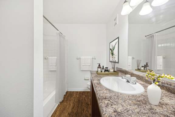 A bathroom with a sink, mirror, and a vase of flowers.