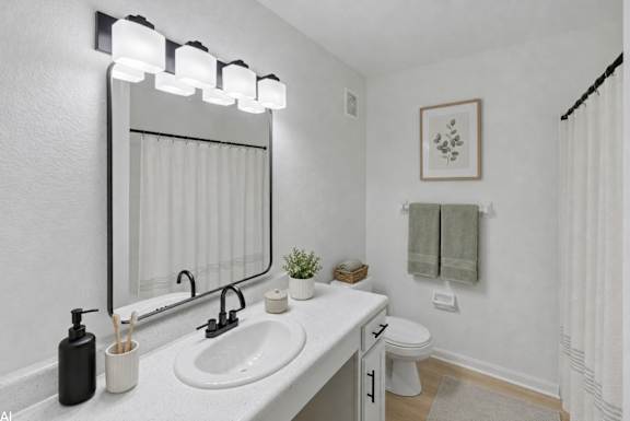 A bathroom with a white sink and a mirror above it.