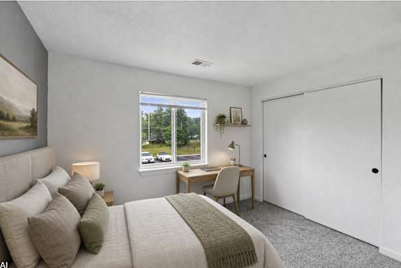 A bedroom with a large bed and a desk with a chair.