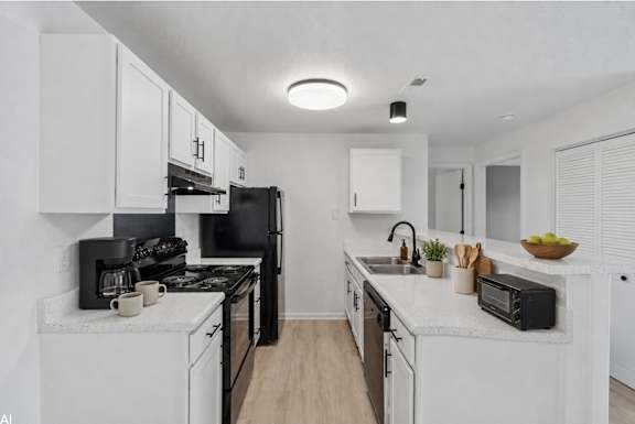 A modern kitchen with black appliances and white cabinets.
