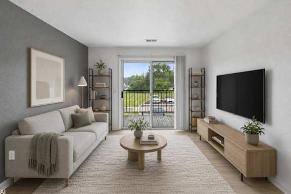 A living room with a grey couch, a coffee table, a flat screen TV, and a large window.