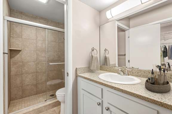 A bathroom with a walk-in shower, toilet, and sink.