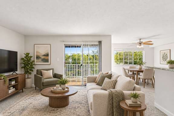 A living room with a flat screen TV, a sofa, a coffee table, and a dining table.
