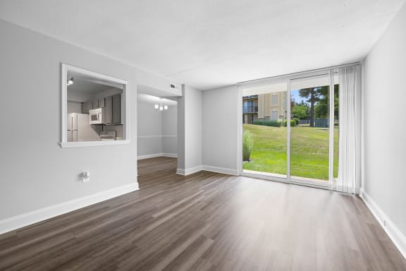 an empty living room with a large window and wood flooring