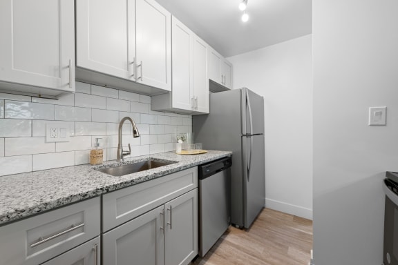a kitchen with white cabinets and a sink and a refrigerator at Gainsborough Court Apartments, Fairfax, 22030