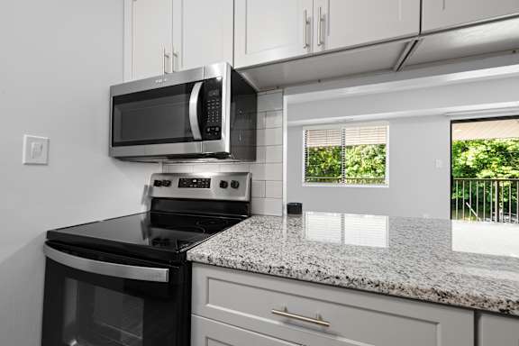 an updated kitchen with granite counter tops and black appliances at Gainsborough Court Apartments, Fairfax