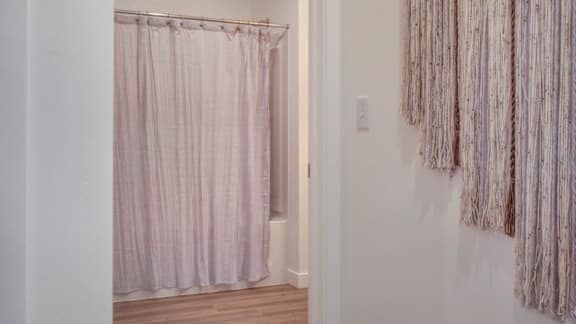 A room with a pink curtain and a white wall.
