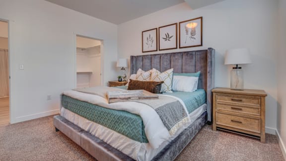 A bedroom with a large bed, a nightstand, and a carpeted floor.