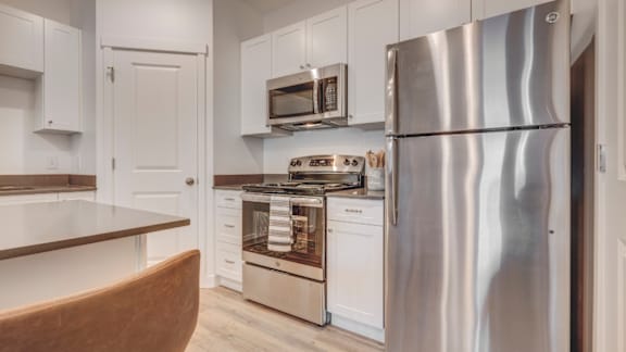 A modern kitchen with a stainless steel refrigerator and white cabinets.
