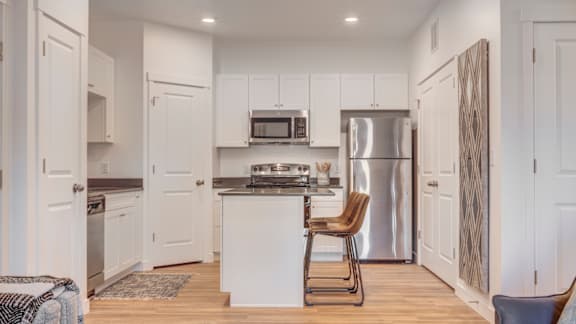 A kitchen with white cabinets and a stainless steel refrigerator.