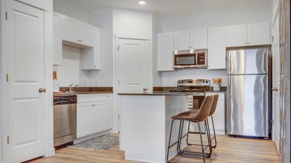 A kitchen with white cabinets and a wooden floor.