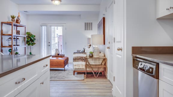 A kitchen with white cabinets and a wooden floor.