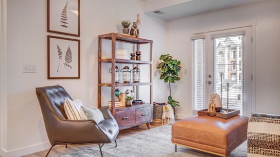 A living room with a brown leather chair and a wooden cabinet with glass doors.
