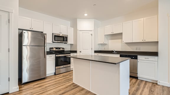 A modern kitchen with white cabinets and stainless steel appliances.
