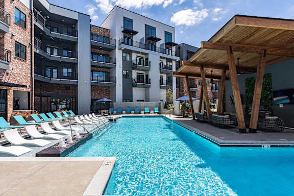 A swimming pool in front of a modern apartment building.
