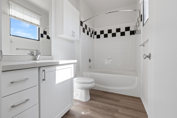 a bathroom with white cabinets and a white toilet and a bath tub