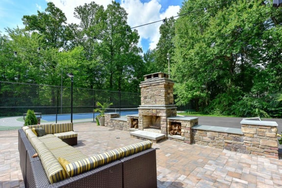 a backyard with a stone fireplace and a tennis court in the background