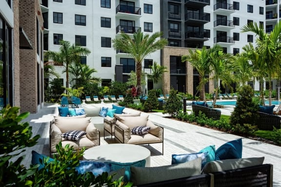 a patio with couches and tables in front of an apartment building