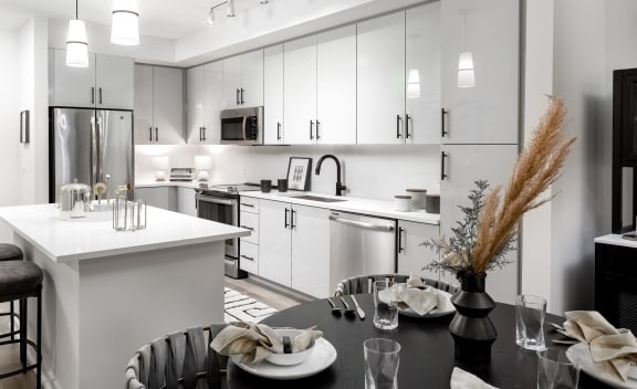 a black and white kitchen and dining area with a black table and chairs