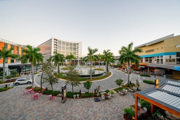 a fountain and seating area in the middle of a plaza with buildings in the background