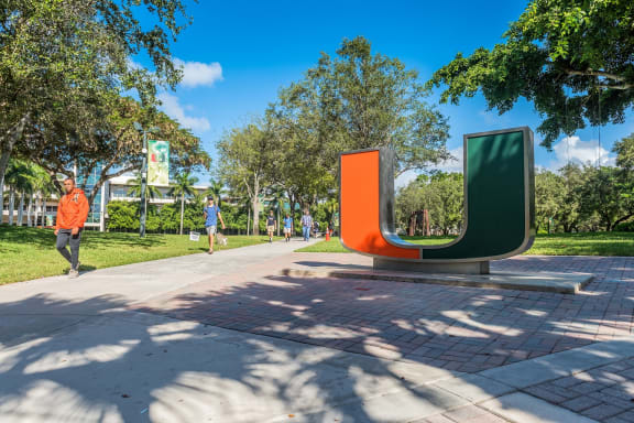 a man in an orange jacket walks past a large sculpture in a park