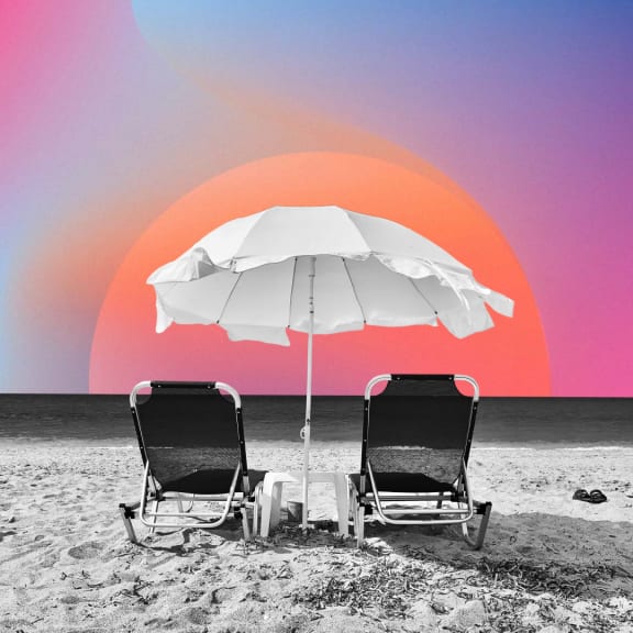 two beach chairs under an umbrella on the beach with a sunset in the background