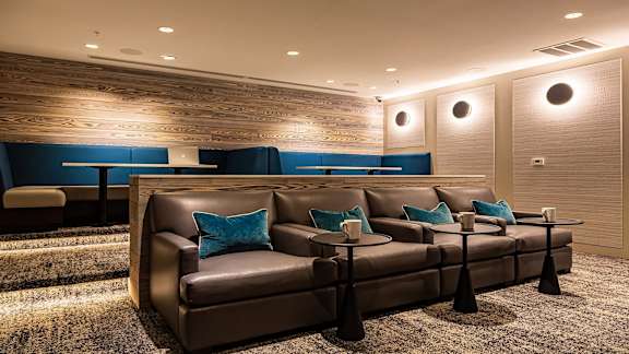 a room with a couch and tables in front of a wall with a wooden accent wall