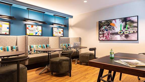 a room with tables and chairs and a tv on the wall
