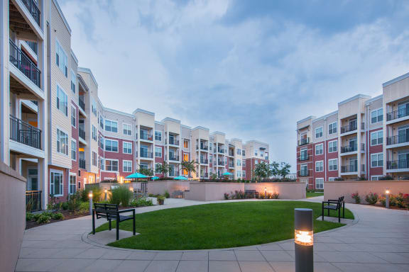 a grassy area with benches in front of an apartment building