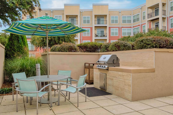 a patio with a grill and table and chairs